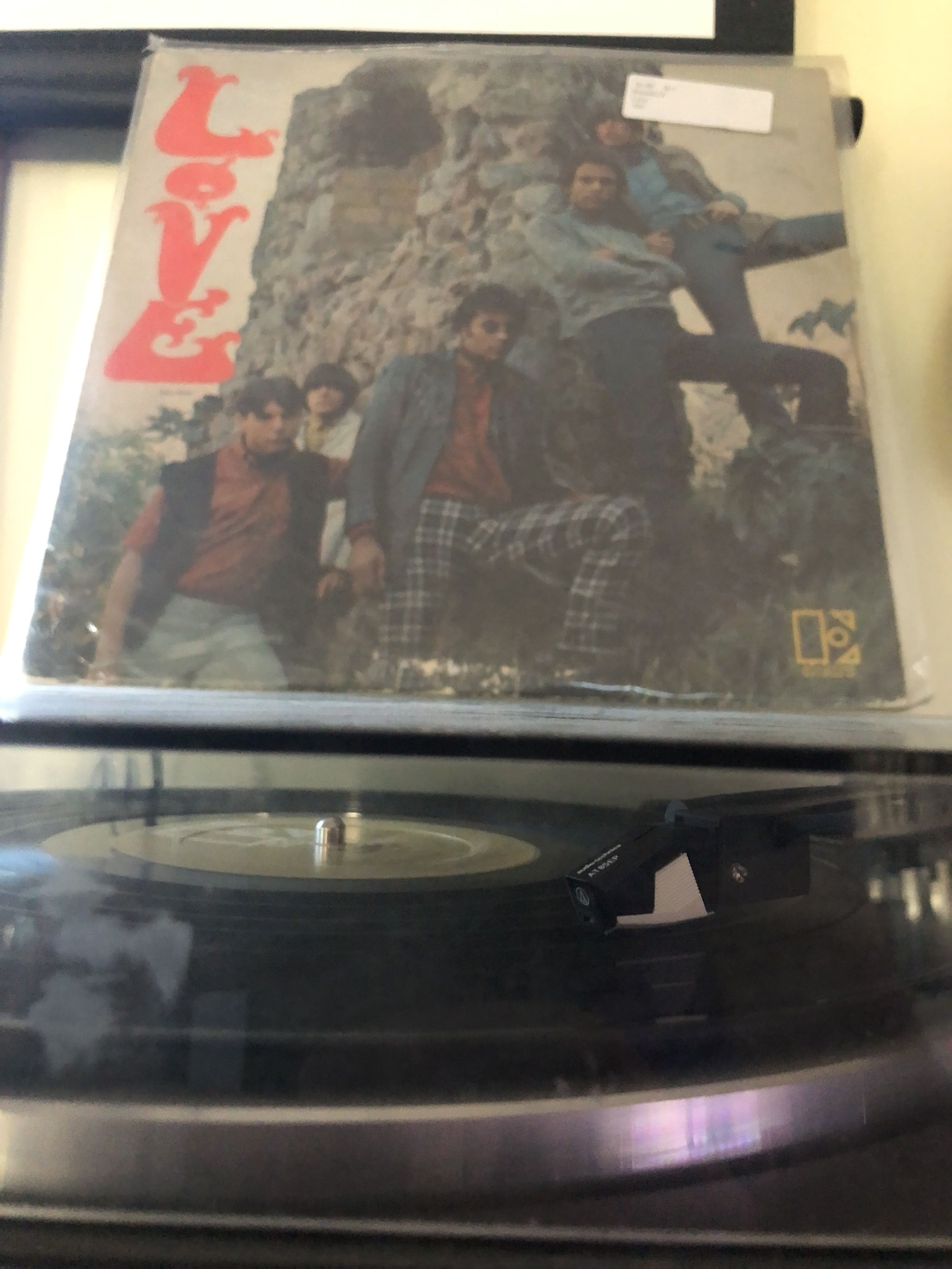 A turntable playing a record with the cover of Love's self-titled album visible.