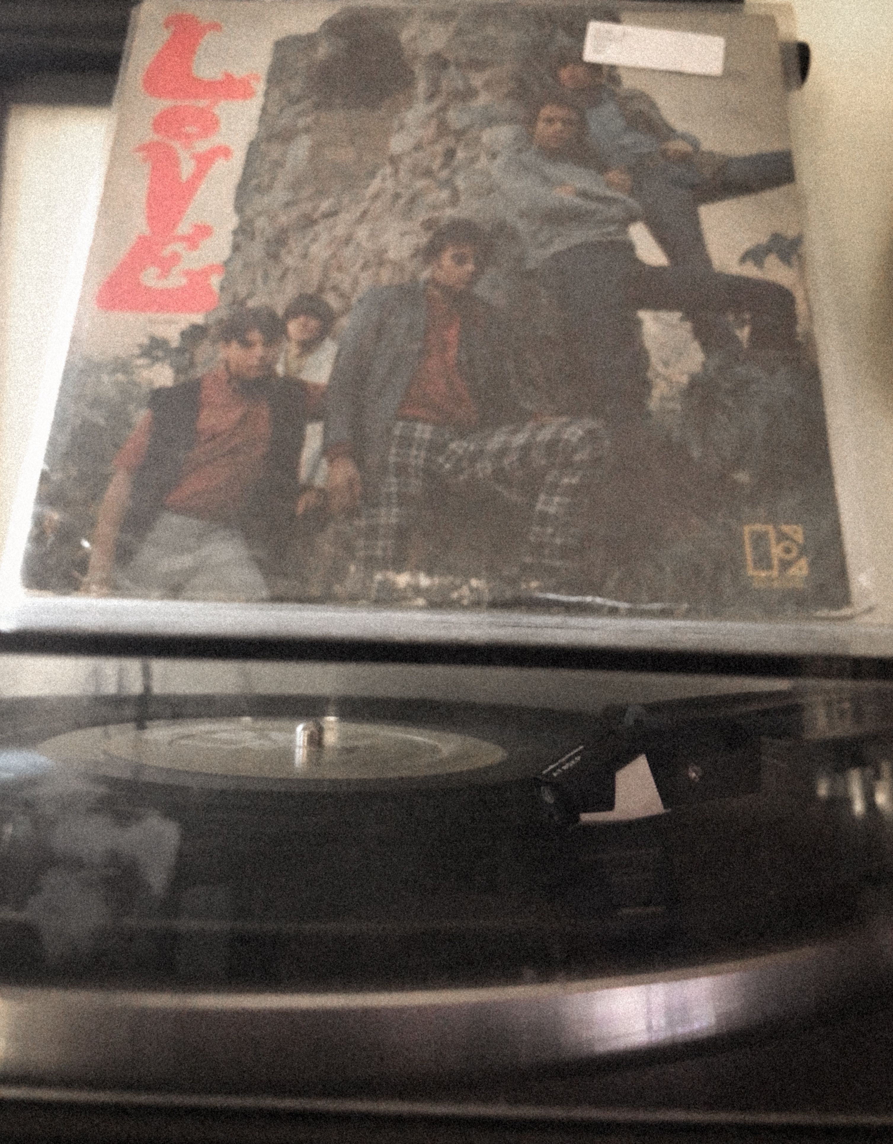 A turntable playing a record with the cover of Love's self-titled album visible.